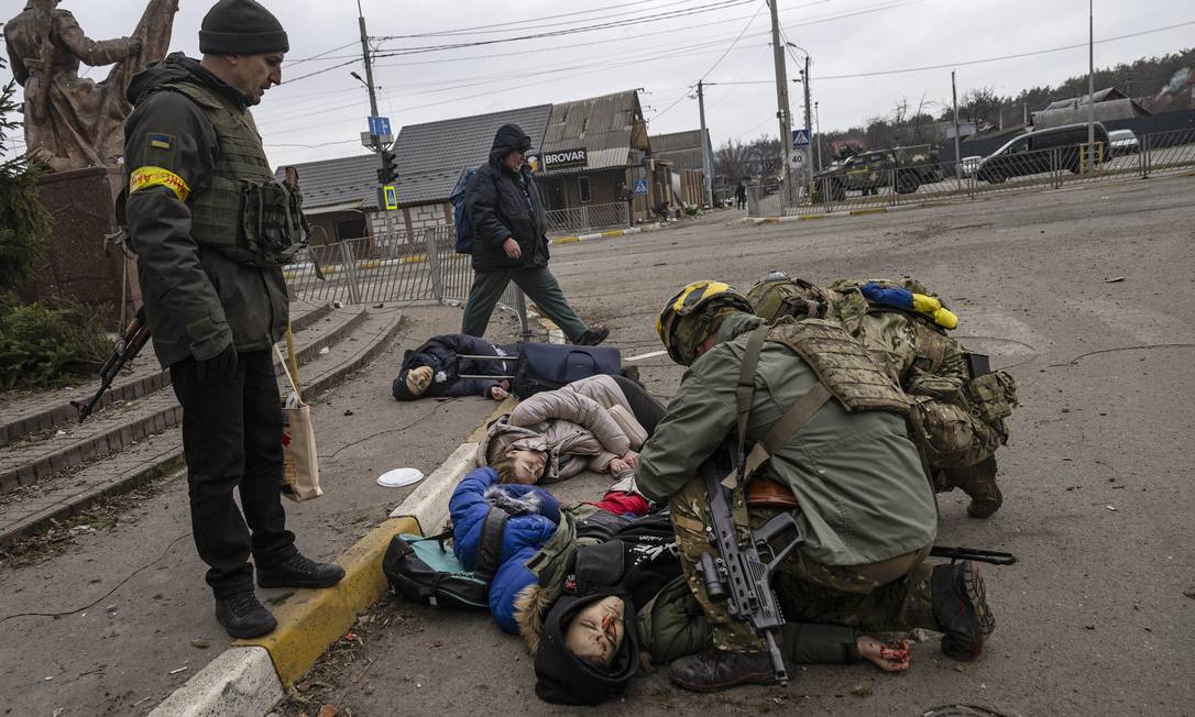 Soldados ucranianos socorrem o pai de uma família atacada neste domingo por morteiros russos. A mãe e os dois filhos morreram Foto: LYNSEY ADDARIO / NYT