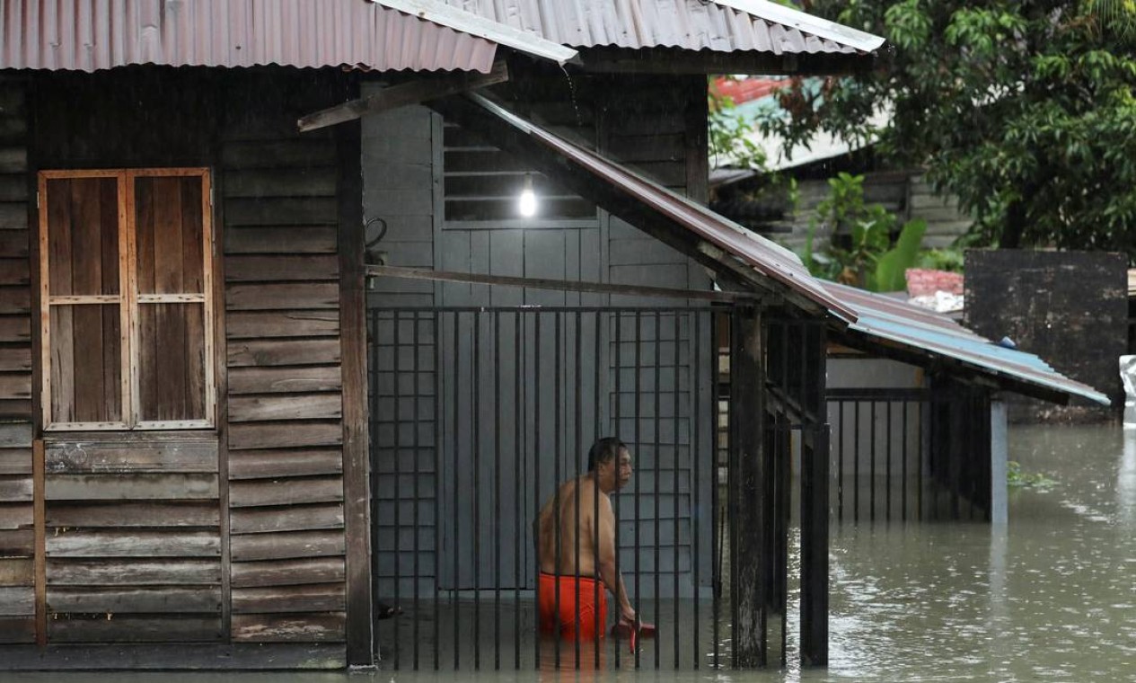 Morador é visto dentro de sua casa parcialmente submersa durante uma enchente, após uma forte chuva em Kuala Lumpur, Malásia Foto: HASNOOR HUSSAIN / REUTERS