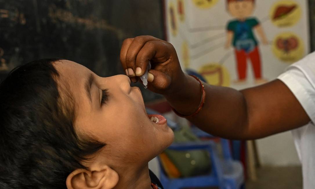 Profissional de saúde vacina criança com a gotinha contra a pólio Foto: ARUN SANKAR / AFP