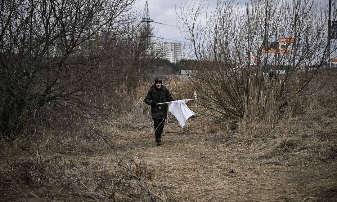 Homem caminha com bandeira branca na cidade de Irpin, a oeste de Kiev Foto: ARIS MESSINIS / AFP