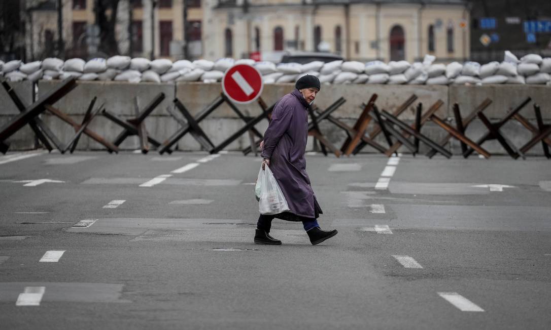 Um mulher atravessa a rua à frente de uma barricada antitanque em Kiev Foto: GLEB GARANICH / REUTERS