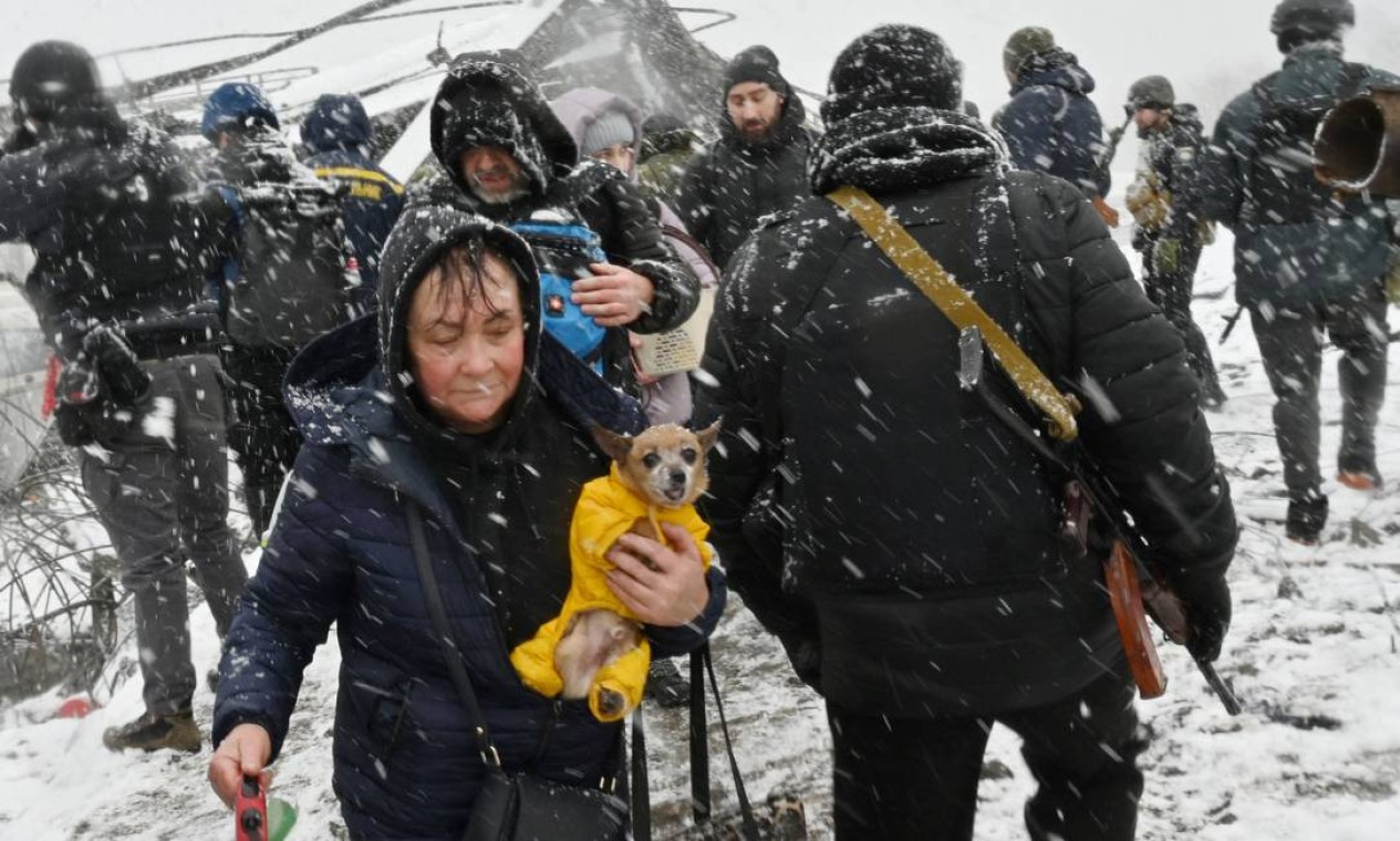 Mulher carrega seu cachorro durante a evacuação por civis da cidade de Irpin, a noroeste de Kiev Foto: SERGEI SUPINSKY / AFP