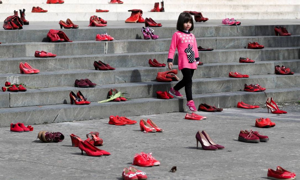 Jovem observa instalação de sapatos vermelhos femininos exibidos em uma escada, como um símbolo para denunciar a violência contra as mulheres, em Tirana, Albânia Foto: FLORION GOGA / REUTERS