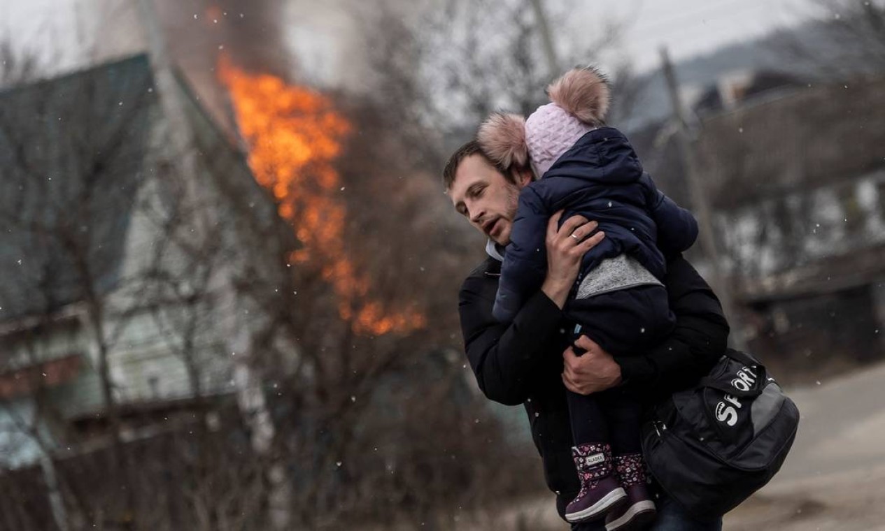 Um homem e uma criança escapam da cidade de Irpin após bombardeios pesados na única saída, enquanto tropas russas avançam para a capital de Kiev Foto: CARLOS BARRIA / REUTERS