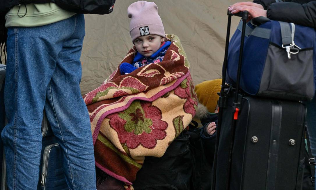 Criança descansa em malas na fronteira ucraniana com a Polônia, em Medyka, na Polônia Foto: LOUISA GOULIAMAKI / AFP