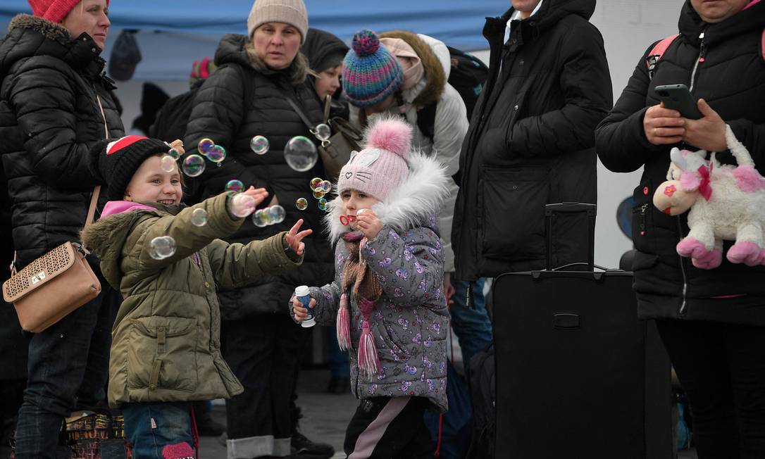 Crianças brincam enquanto esperam ônibus com destino à Alemanha, para lar temporário Foto: LOUISA GOULIAMAKI / AFP