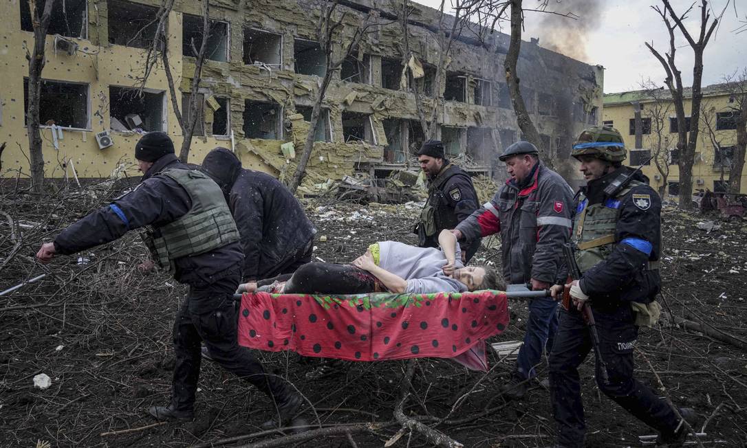 Funcionários e voluntários de emergência ucranianos carregam uma mulher grávida ferida da maternidade danificada pelo bombardeio em Mariupol, na Ucrânia, nesta quarta-feira, 9 de março de 2022 Foto: EVGENIY MALOLETKA / Agência O Globo