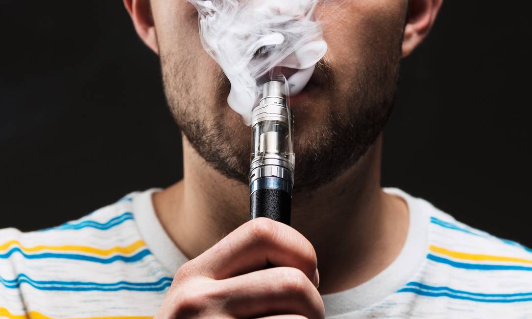 The face of vaping young man on black studio background