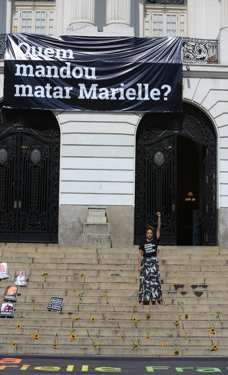 Mônica Benício posa de punho cerrado abaixo de cartaz com a pergunta que completa quatro anos sem resposta Foto: FramePhoto / Agência O Globo