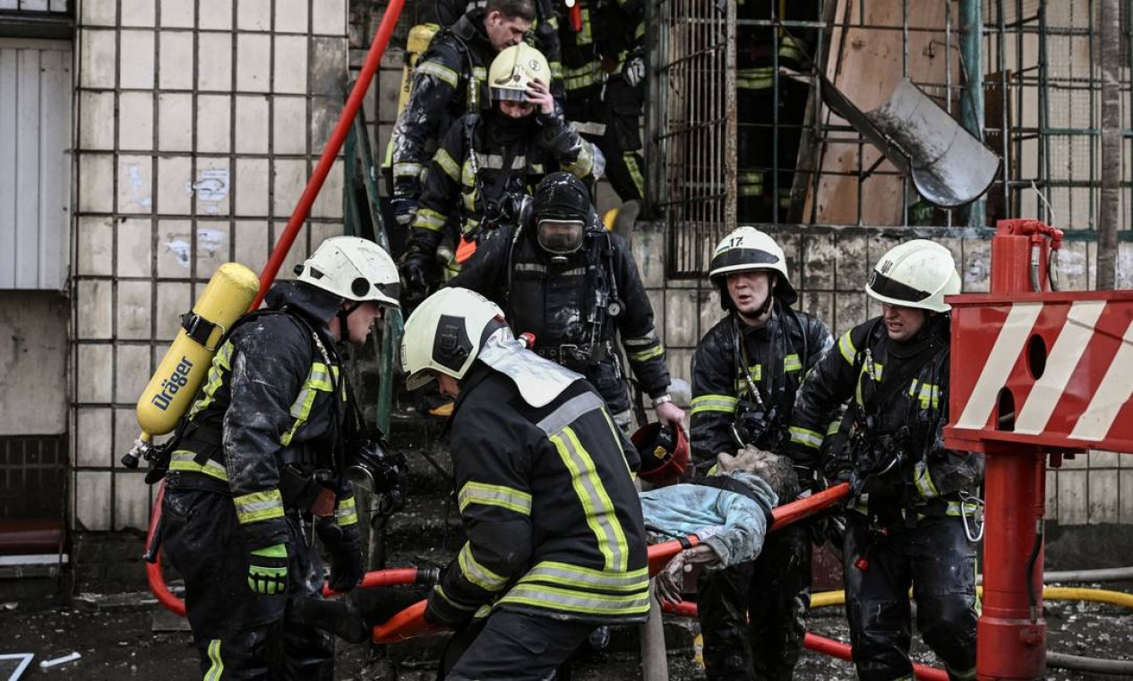 Bombeiros removem o corpo de uma mulher de um prédio de apartamentos destruído em Kiev Foto: ARIS MESSINIS / AFP