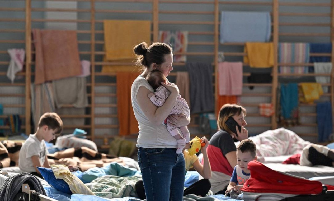 Mulher segura seu bebê de dois meses em um abrigo temporário em uma academia de uma escola em Przemysl, perto da fronteira ucraniana-polonesa Foto: LOUISA GOULIAMAKI / AFP