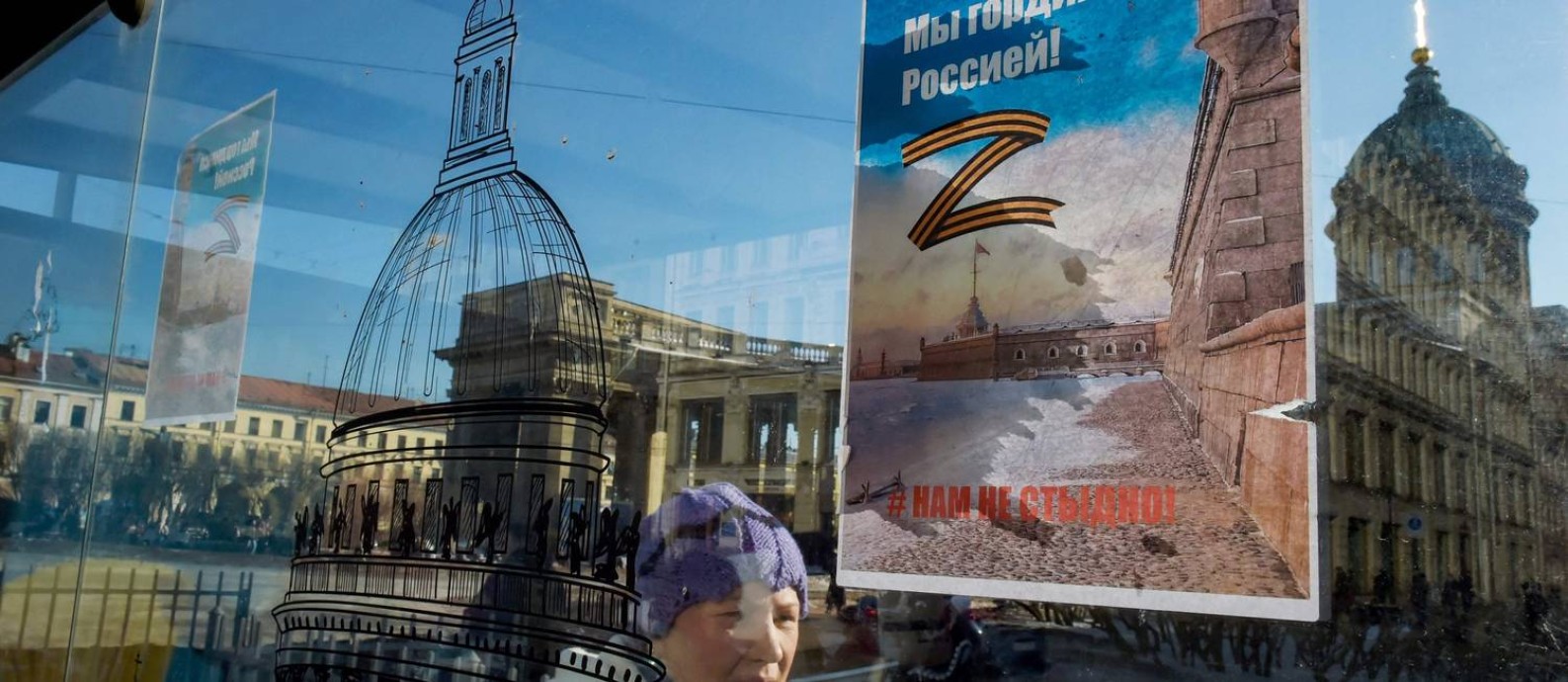 Mulher passa diante de cartaz a favor da guerra na Ucrânia, colado em ponto de ônibus da Nevsky Prospekt, principal avenida de São Petersburgo Foto: - / AFP