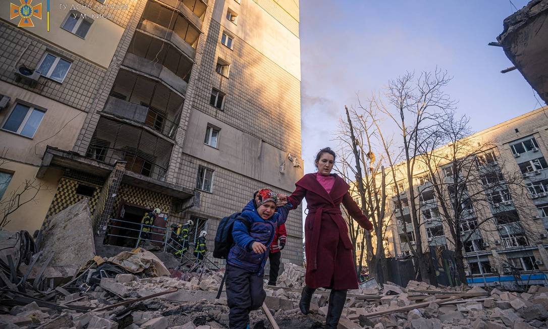 Mulher e criança deixam prédio residencial atacado pela artilharia russa em Kiev, capital da Ucrânia Foto: SERV IÇO DE EMERGÊNCIA DA UCRÂNIA / via REUTERS