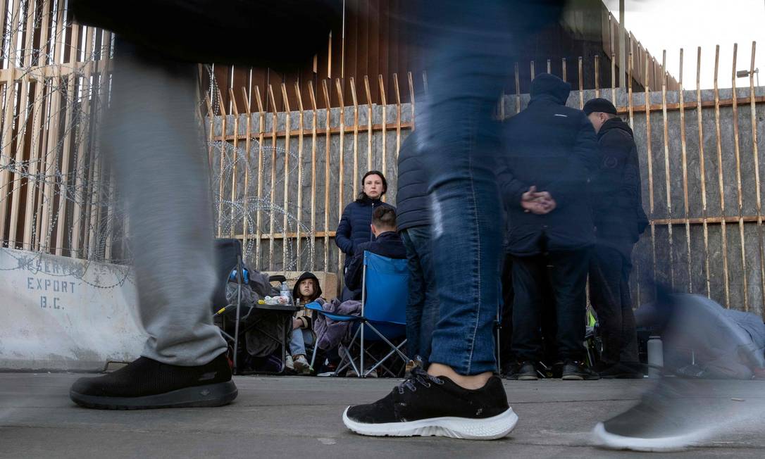 Família de imigrantes russos aguarda liberação para entrar nos EUA pela travessia de San Ysidro, no México: ucranianos têm passe livre Foto: GUILLERMO ARIAS / AFP