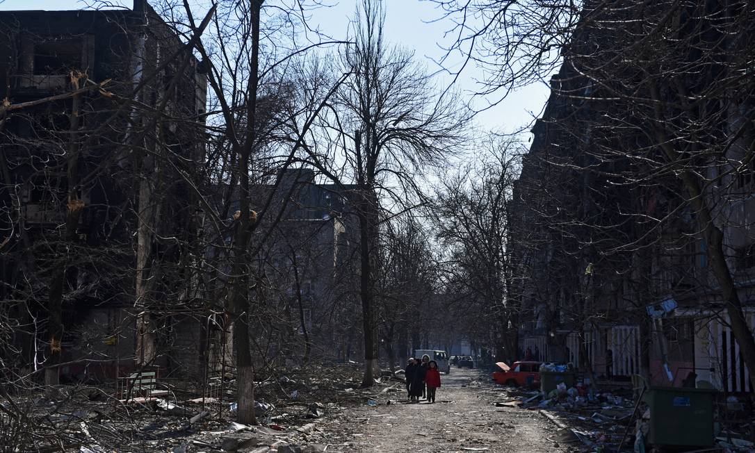 Moradores caminham perto de edifícios residenciais danificados durante o conflito Ucrânia-Rússia na cidade portuária sitiada de Mariupol, Ucrânia, em 18 de março de 2022 Foto: STRINGER / REUTERS