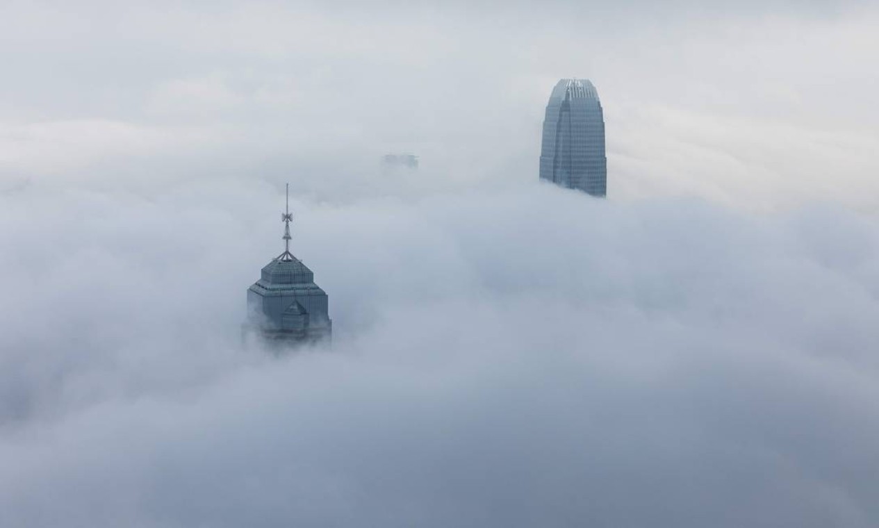 Os edifícios The Center (esquerda) e International Finance Center (direita), tendo mais de 300 metros de altura, são vistos quase totalmente encobertos por neblina, em Hong Kong Foto: DALE DE LA REY / AFP