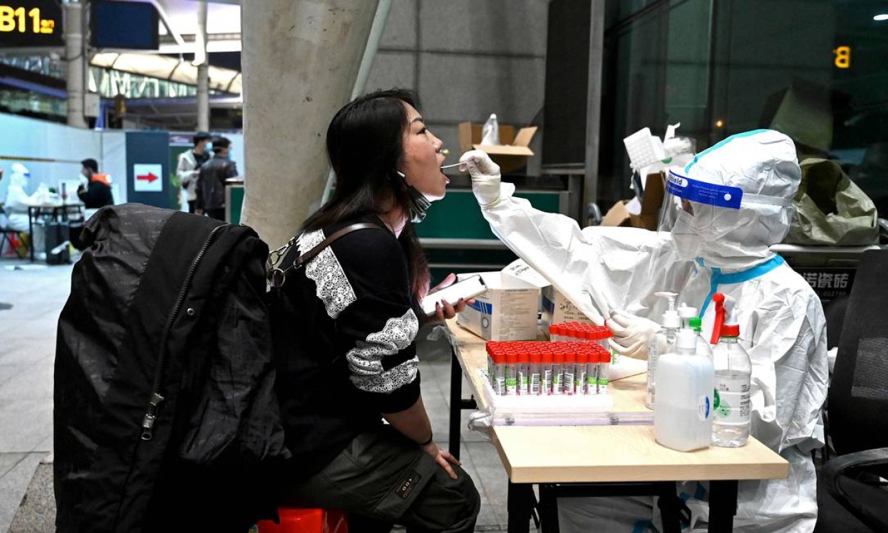 Profissional de saúde coleta de passageiro que chega no Aeroporto Internacional de Guangzhou Baiyun, na província de Guangdong, no sul da China, como medida preventiva contra o coronavírus Foto: NOEL CELIS / AFP