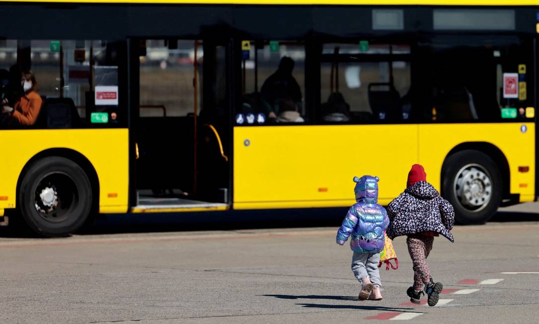 Crianças refugiadas da Ucrânia correm para ônibus após chegarem em Berlin, na Alemanha Foto: HANNIBAL HANSCHKE / REUTERS