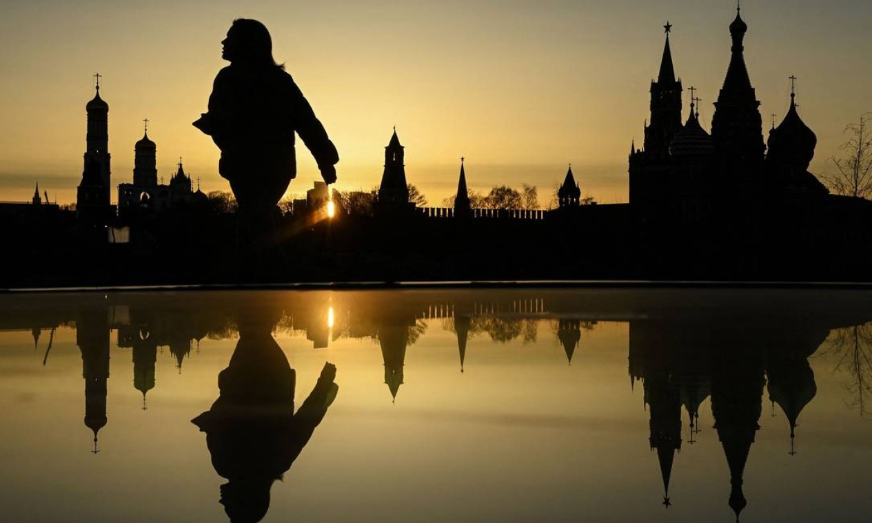 Mulher caminha no parque Zaryadye em frente à Catedral Ivan, o Grande, a torre Spasskaya do Kremlin e a Catedral de São Basílio durante o pôr do sol no centro de Moscou, Rússia Foto: - / AFP