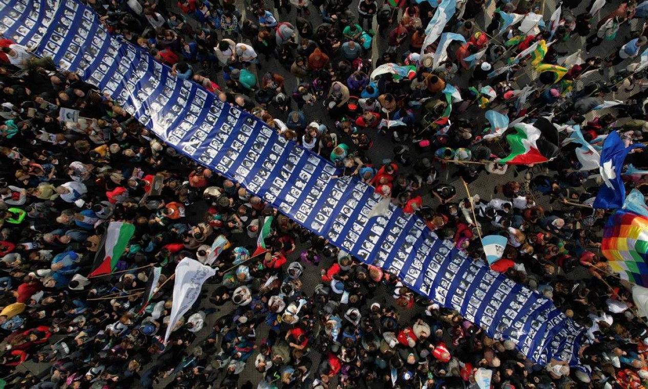 Centenas de pessoas carregam uma grande faixa com retratos de pessoas desaparecidas durante a ditadura militar (1976-1983), durante manifestação que marca o 46º aniversário do golpe, na Plaza de Mayo, em Buenos Aires. Cerca de 30.000 pessoas desapareceram após serem presas durante a ditadura argentina Foto: ELENA BOFFETTA / AFP
