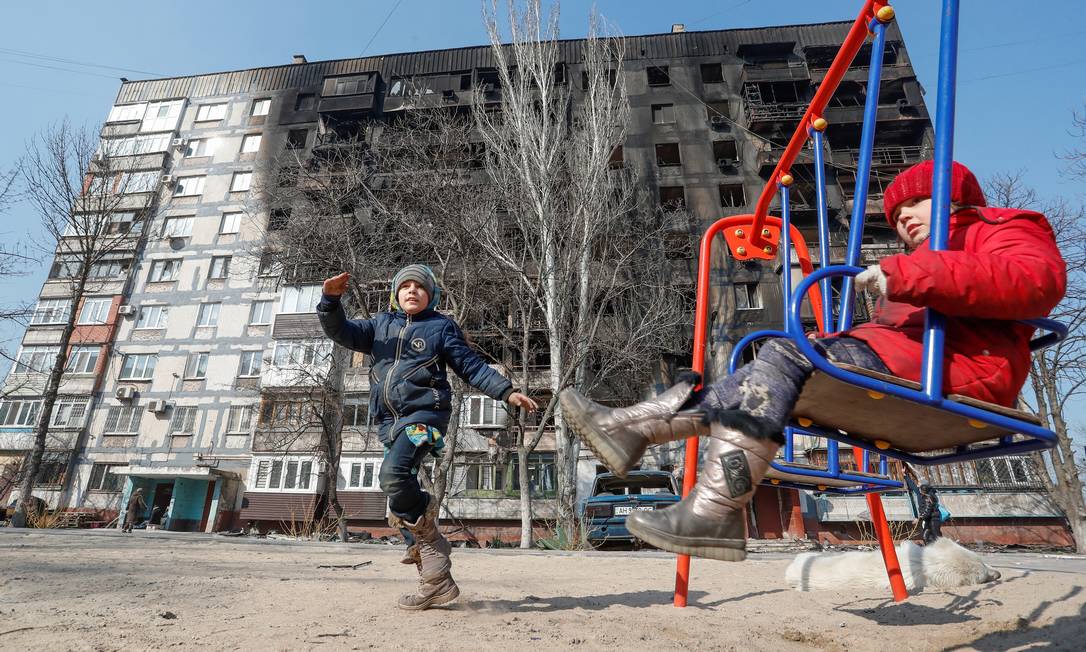 Crianças brincam em frente a um prédio danificado durante o conflito Ucrânia-Rússia, em Mariupol, Ucrânia Foto: ALEXANDER ERMOCHENKO / Reuters