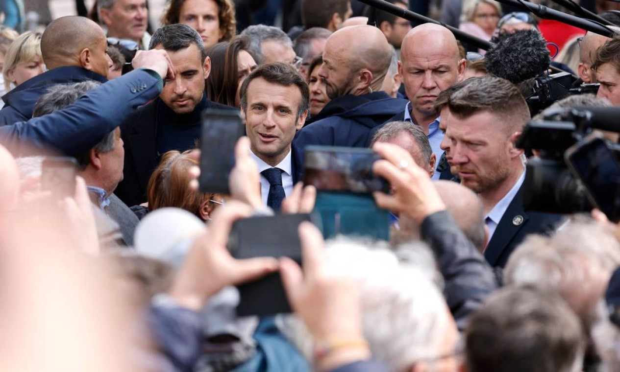 Moradores tiram fotos com o presidente francês e candidato do partido La Republique en Marche (LREM) para a eleição presidencia,l Emmanuel Macron, enquanto caminha na rua durante uma visita de campanha em Fouras, oeste da França Foto: LUDOVIC MARIN / AFP