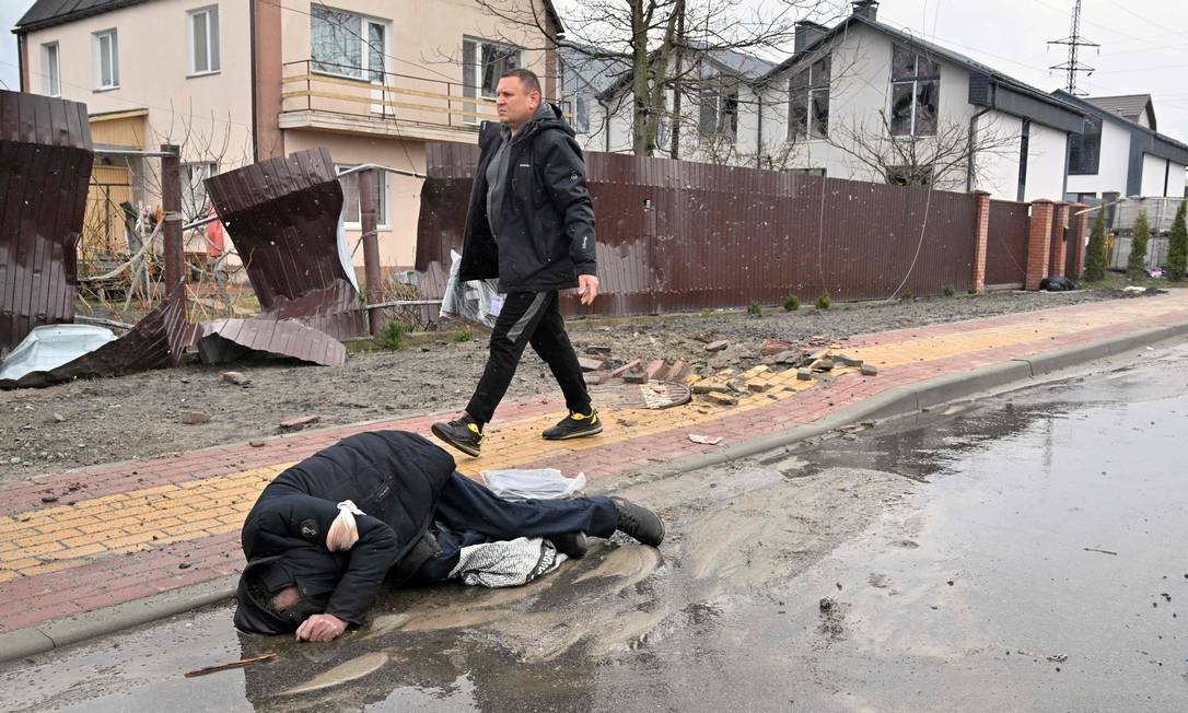Homem caminha próximo a corpo de vítima do massacre russo Foto: SERGEI SUPINSKY / AFP
