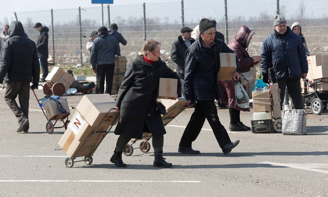 Pessoas transportam caixas com suprimentos doados pela Rússia enquanto aguardam transporte para serem retirados de Mariupol Foto: ALEXANDER ERMOCHENKO / REUTERS