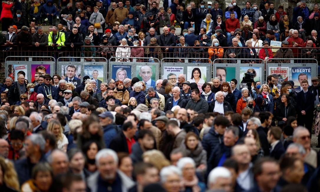 Comício tardio: diante de cartazes dos candidatos, eleitores esperam chegada de Macron a comício em Spezet; ocupado com guerra, ele atrasou campanha em votação na qual poder aquisitivo é a maior preocupação Foto: STEPHANE MAHE / REUTERS/5-4-2022