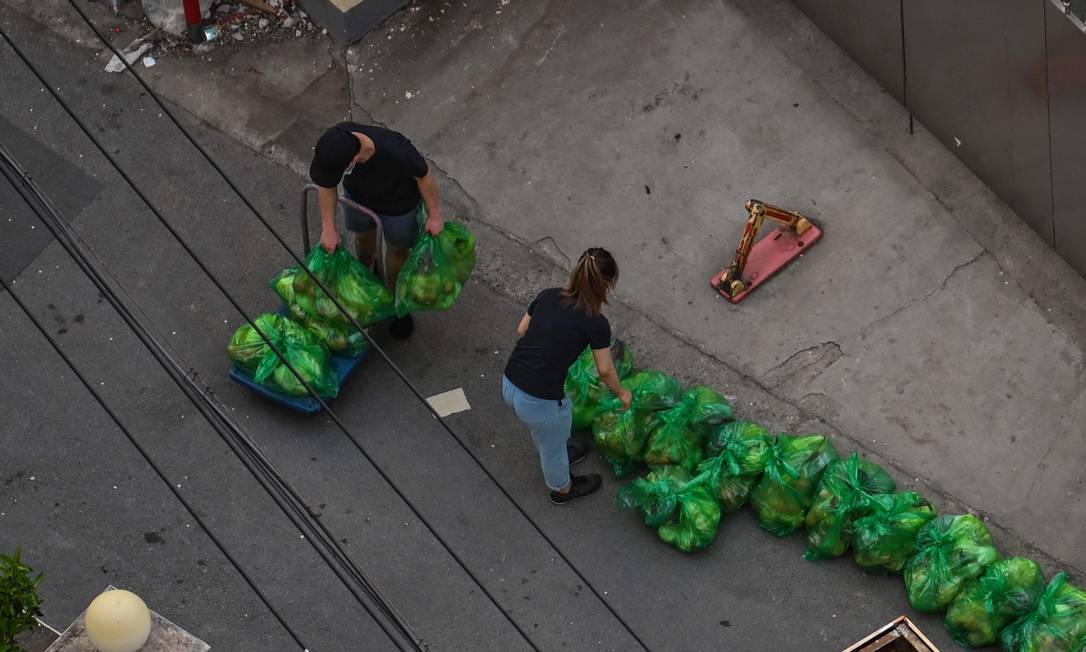 Moradores recolhem sacolas com alimentos durante a quarentena no distrito de Jing'an, em Xangai Foto: HECTOR RETAMAL / AFP