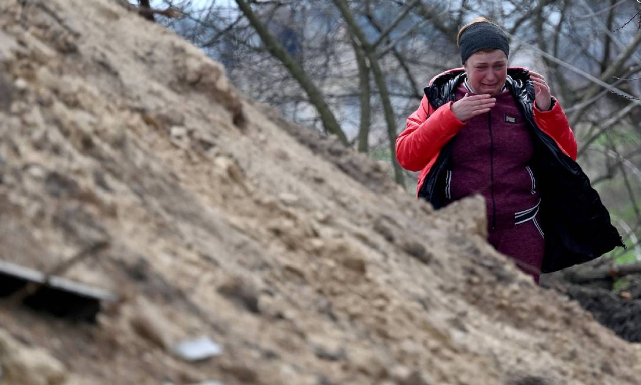 Parente reage depois que o corpo de um civil foi exumado de uma cova rasa perto de sua casa na vila de Andriivka, região de Kiev, Ucrânia Foto: SERGEI SUPINSKY / AFP