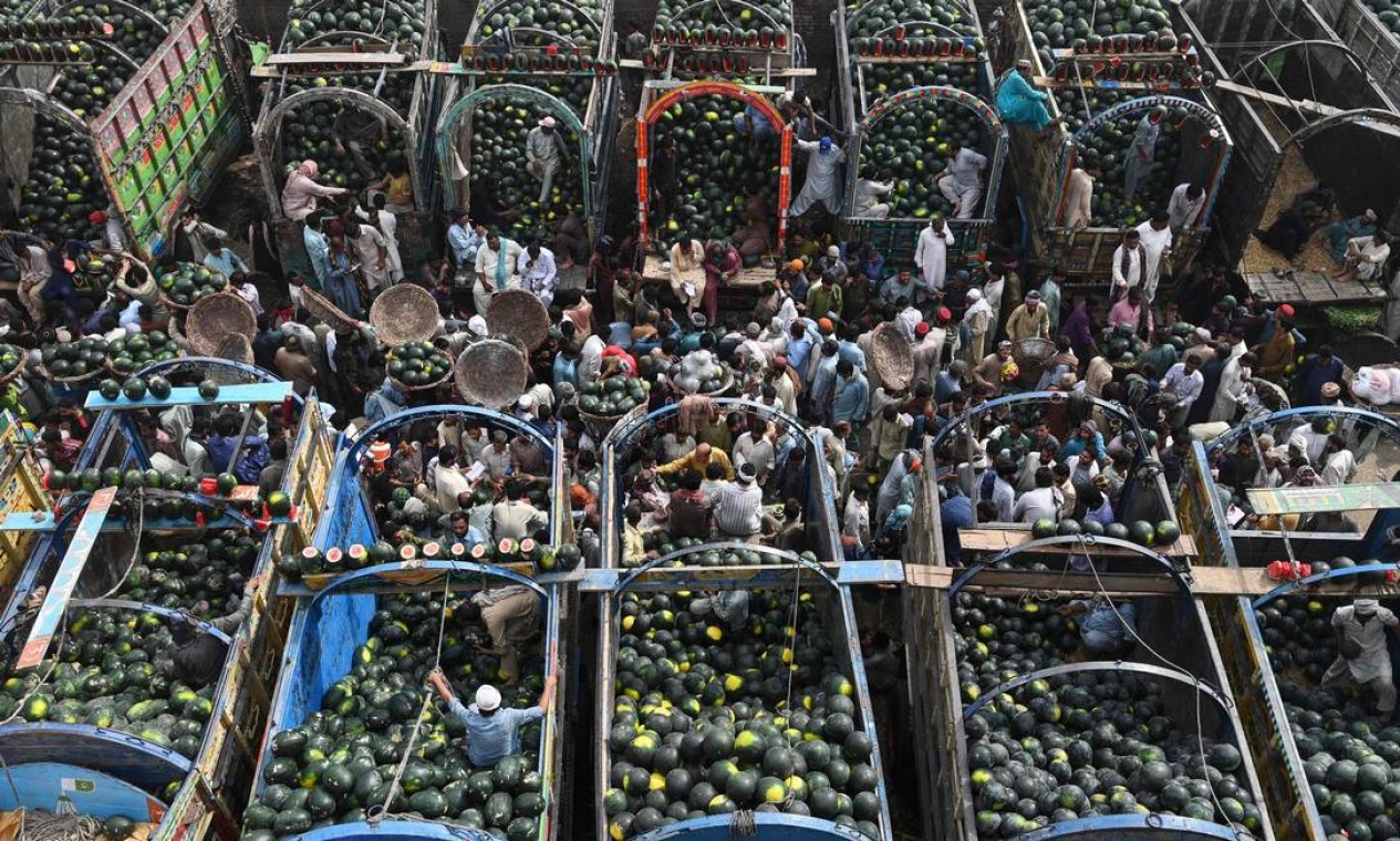 Pessoas negociam melancias em um mercado de frutas em Lahore, Paquistão Foto: ARIF ALI / AFP