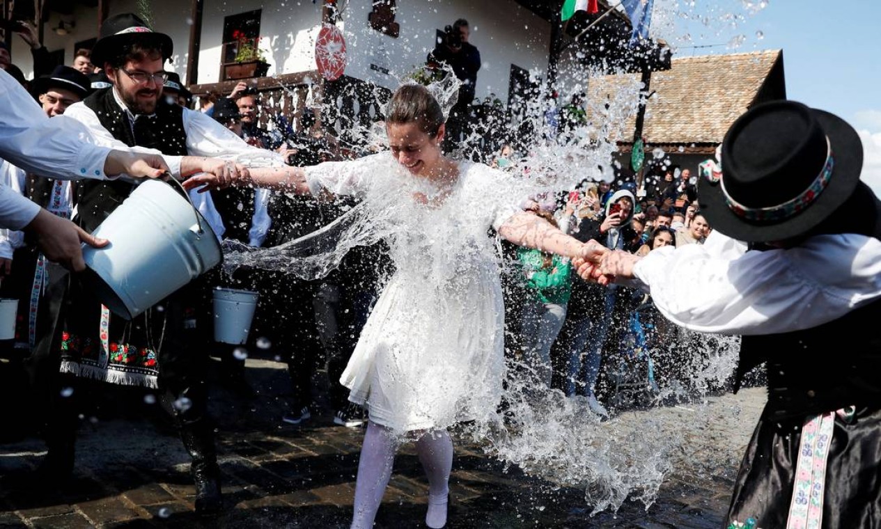 Homens jogam água gelada em mulher vestida em trajes tradicionais durante tradicional celebração da Páscoa em Holloko, Hungria. O ritual com banho de água gelada representa a fertilidade Foto: BERNADETT SZABO / REUTERS