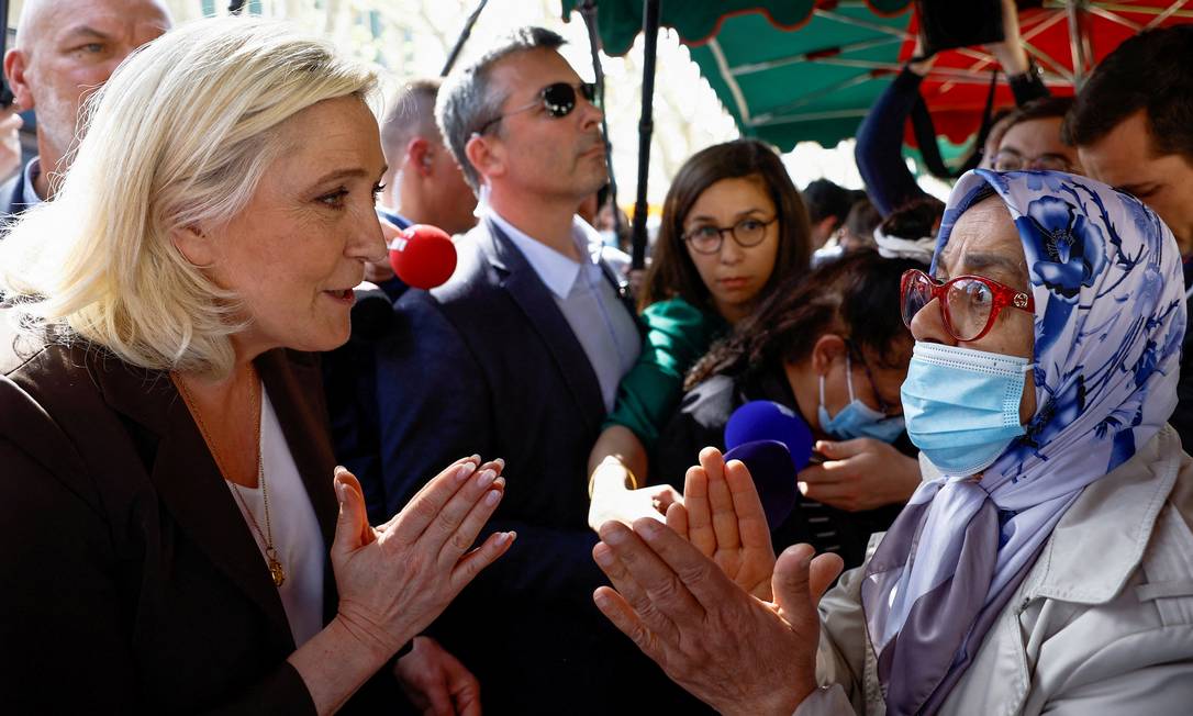 A candidata nacionalista à Presidências da França, Marine Le Pen, confrontada por uma mulher vestindo hijab durante visita a um mercado em Pertuis Foto: Christian Hartmann / Reuters