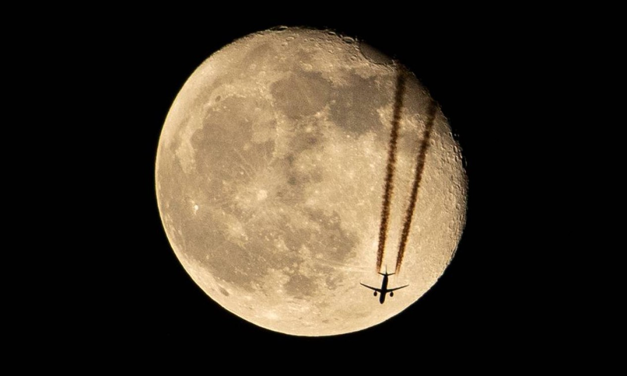 Aeronave sobrevoa a cidade de Basra, no sul do Iraque, passando pela lua minguante Foto: HUSSEIN FALEH / AFP
