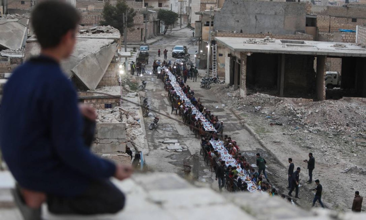 Sírios se reúnem em uma área fortemente danificada para o iftar (a quebra do jejum durante o ramadã), no leste da Síria Foto: BAKR ALKASEM / AFP