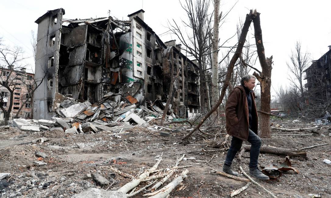 Um homem caminha em frente a um prédio em ruínas na cidade portuária de Mariupol Foto: Alexander Ermochenko / Reuters