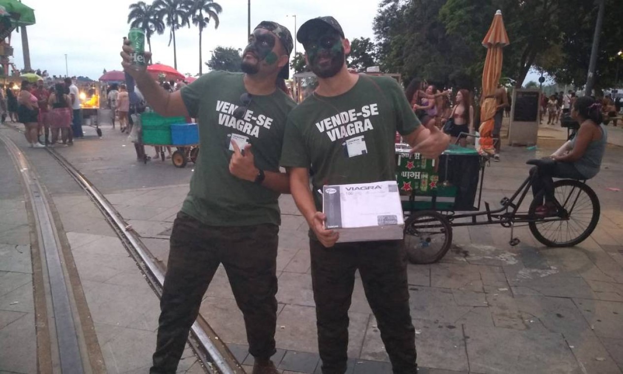 Soldados do Viagra: os foliões Michael Rogers, de 34 anos, e João Victor Félix, de 25, se camuflaram em referência ao Exército e a aprovação de compra de mais de 35 mil comprimidos do medicamento para as Forças Armadas; "Vende-se viagra", diz a placa Foto: Jéssica Marques