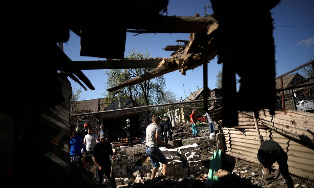 Homens retiram escombros de casa destruída após bombardeio em Zaporizhzhia, onde britânicos foram capturados Foto: UESLEI MARCELINO / REUTERS
