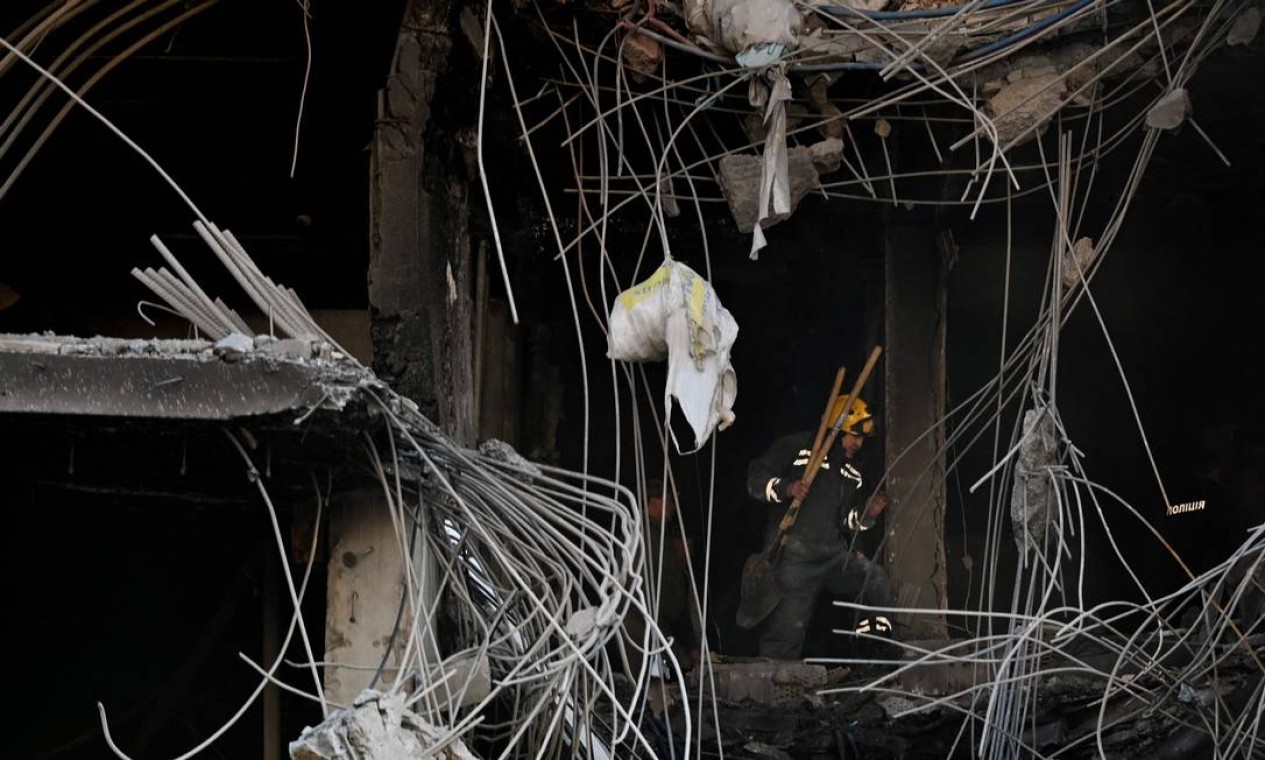 Trabalhador limpa destroços em um prédio destruído após ataques russos Foto: SERGEI SUPINSKY / AFP