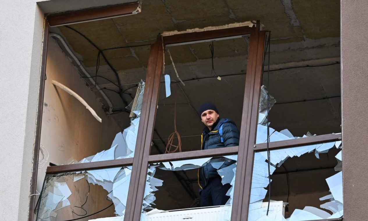 Um morador local olha por uma janela quebrada. Ataques russos atingiram Kiev nesta quinta e quinta-feira (28) Foto: GENYA SAVILOV / AFP
