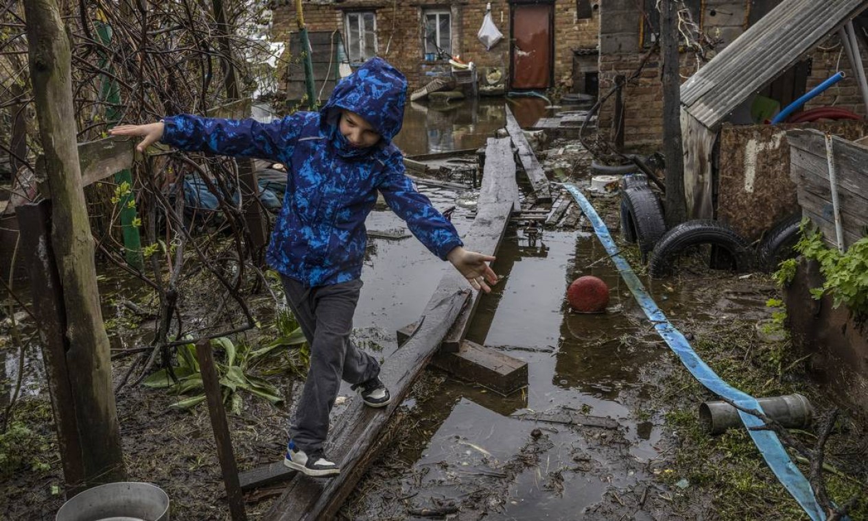 Uma criança caminha sobre pranchas de madeira sobre as águas da enchente em Demydiv, uma vila ao norte de Kiev, , com cerca de 750 famílias, das quais cerca de 50 foram inundadas Foto: DAVID GUTTENFELDER / David Guttenfelder/The New York Times