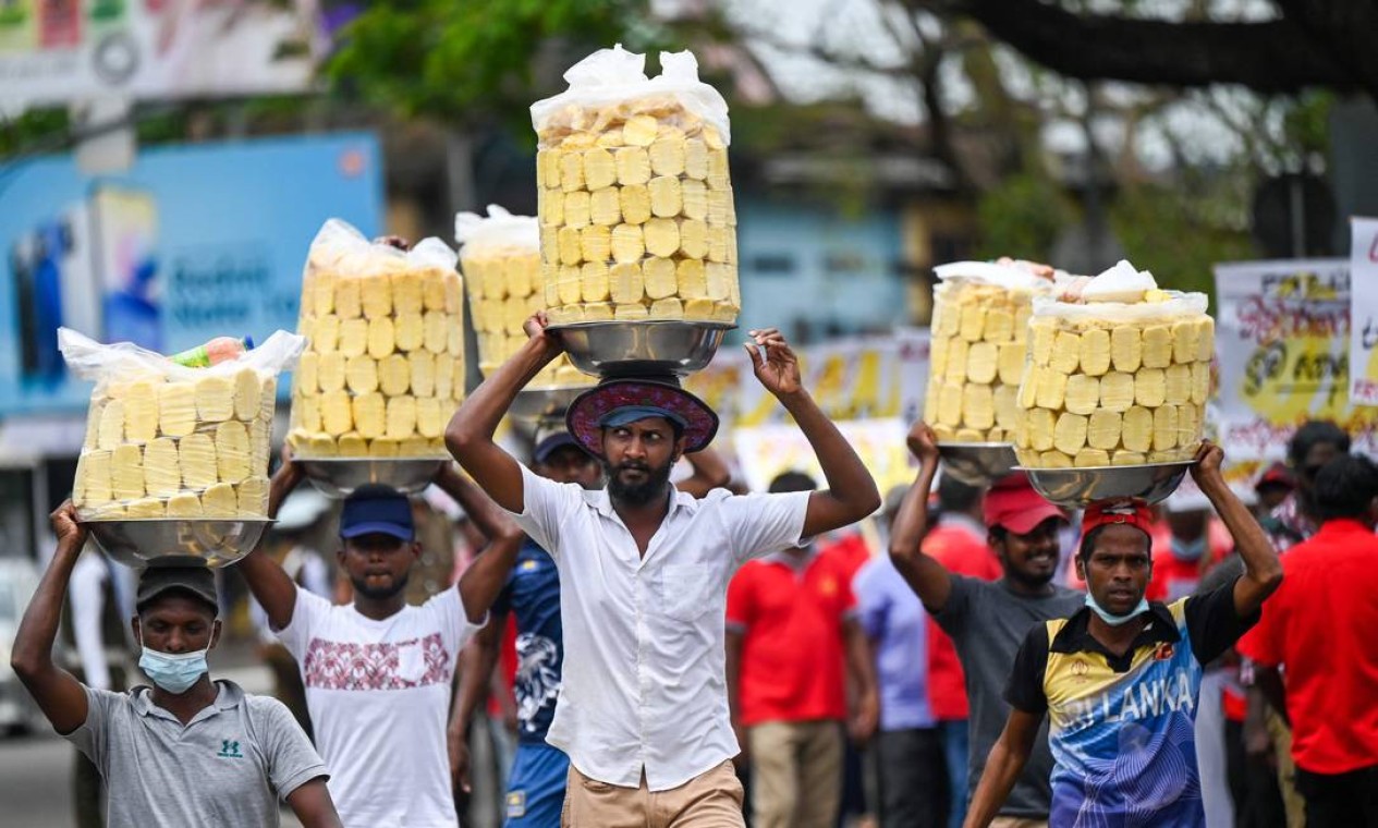 Vendedores de frutas carregam abacaxis sobre a cabeça durante o 1º de Maio em Colombo, no Sri Lanka Foto: ISHARA S. KODIKARA / AFP
