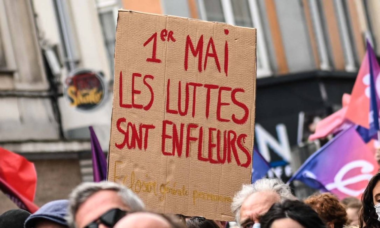 Manifestante segura um cartaz com os dizeres "1º de maio, as lutas florescem", em Lille, norte da França Foto: DENIS CHARLET / AFP