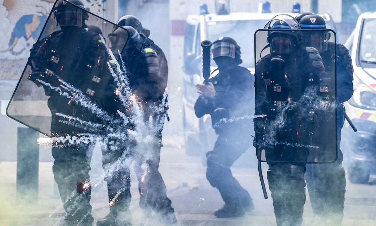 Policiais de choque franceses se protegem de fogos de artifício lançados por manifestantes, à margem do tradicional comício de 1º de maio, em Nantes, oeste da França Foto: SEBASTIEN SALOM-GOMIS / AFP