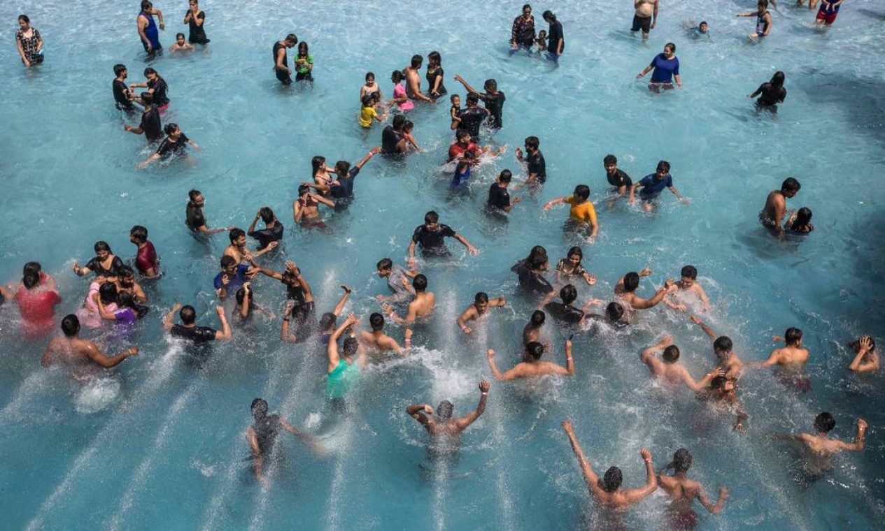 Pessoas se refrescam em uma piscina de ondas durante um dia quente de verão em um parque aquático em Nova Delhi Foto: XAVIER GALIANA / AFP
