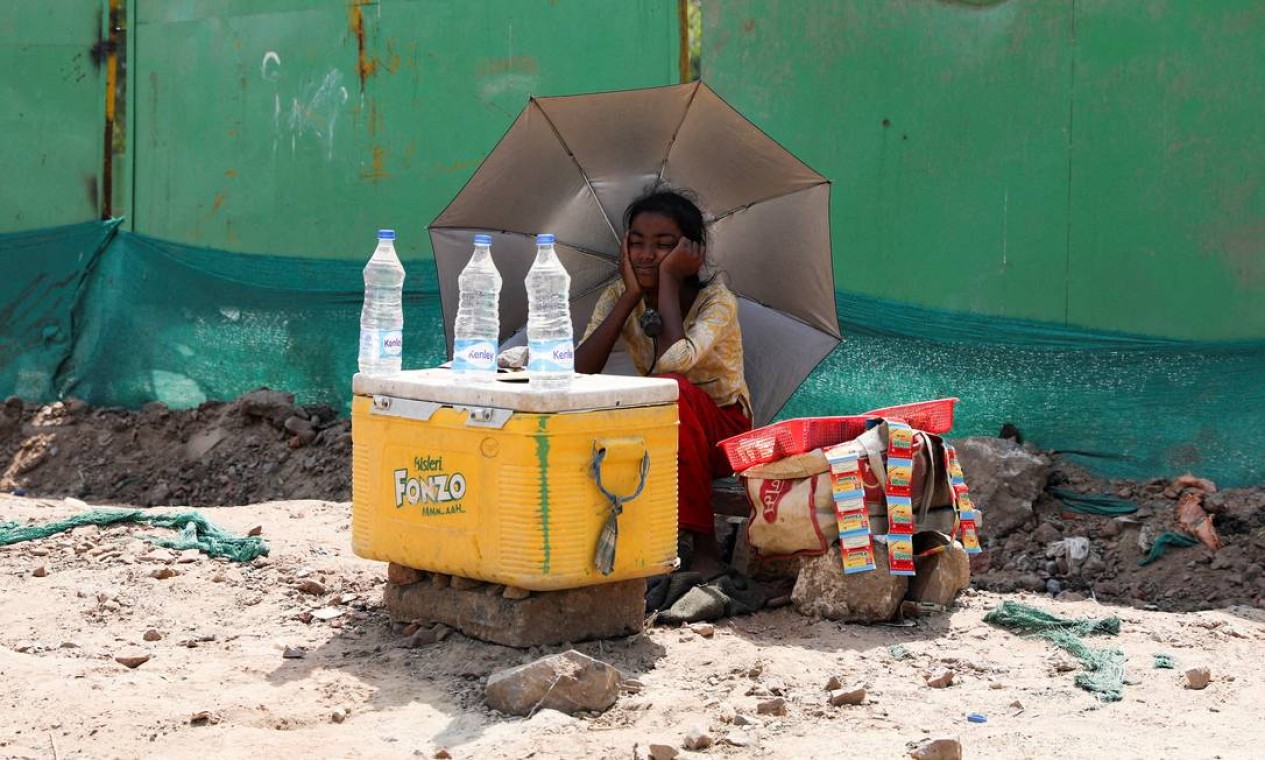 Vendedora água usa um guarda-chuva para se proteger do sol em Nova Délhi. Desde 2010, as ondas de calor mataram mais de 6,5 mil pessoas na Índia Foto: ANUSHREE FADNAVIS / REUTERS