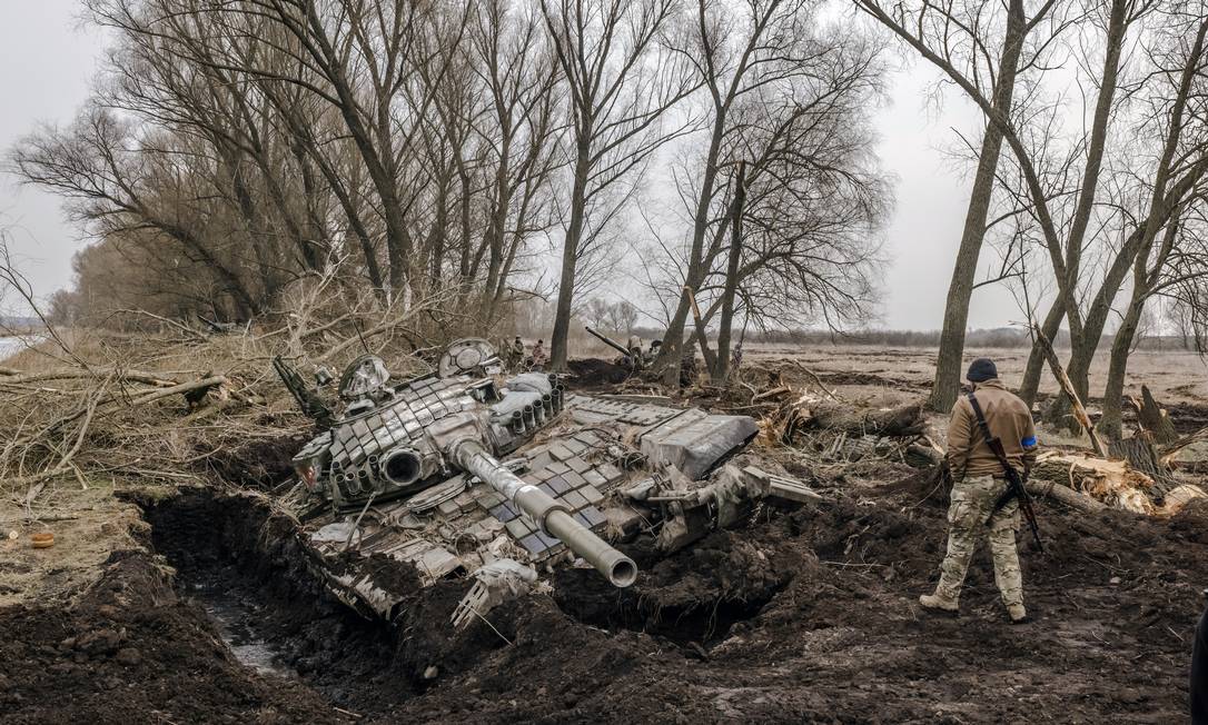 Um soldado ucraniano observa um tanque destruído russo atolado na lama Foto: DANIEL BEREHULAK / NYT