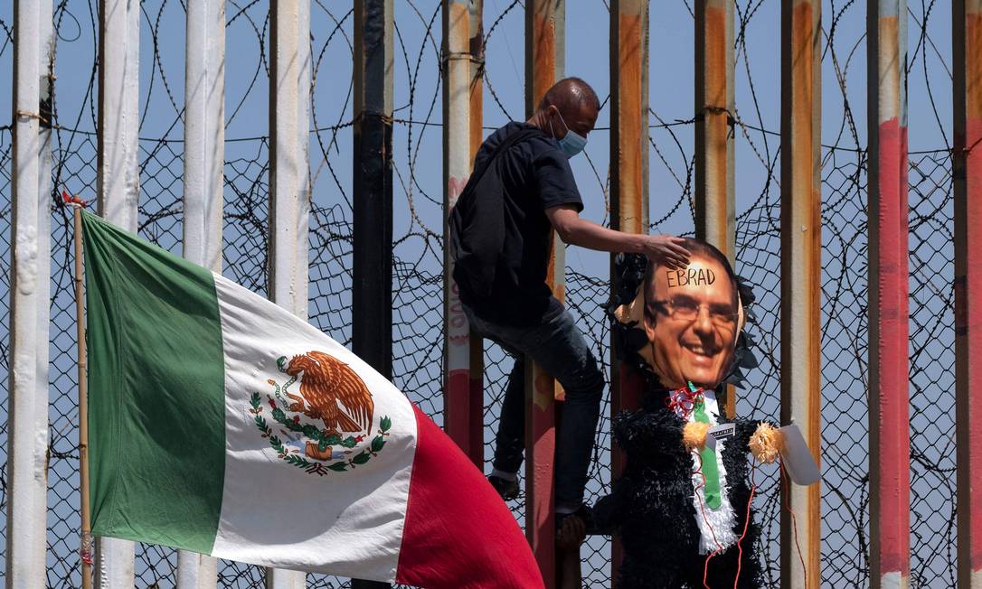 Imigrante tenta superar muro na fronteira entre Estados Unidos e México Foto: GUILLERMO ARIAS / AFP