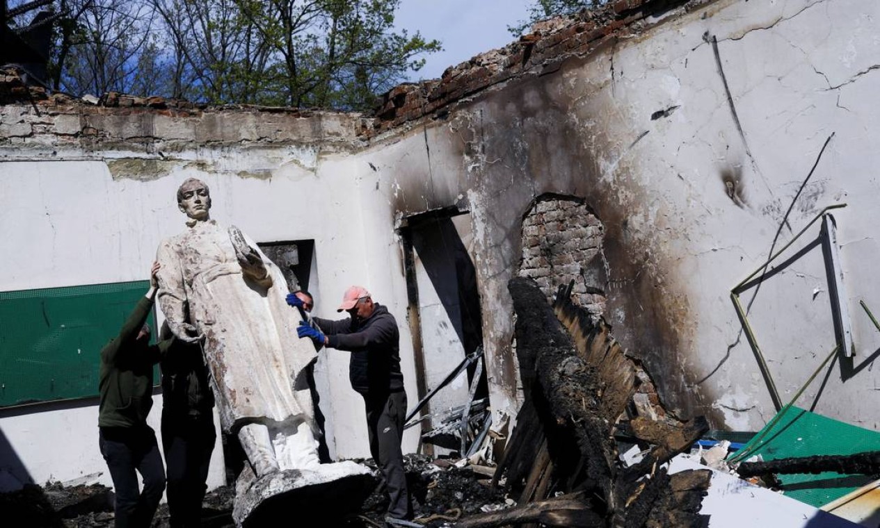 Funcionários removem estátua do filósofo Hryhoriy Skovoroda após bombardeio em museu Foto: RICARDO MORAES / REUTERS